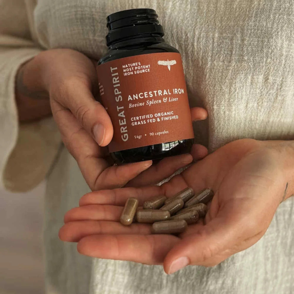 Person holding a bottle of Great Spirit Ancestral Iron with capsules in hand, showcasing natural whole-food heme iron for energy and vitality.