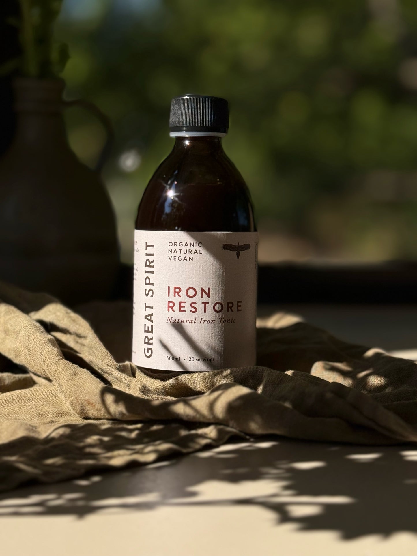 Bottle of Great Spirit Iron Restore 300ml on a textured surface with a blurred natural background.