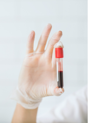 Hand in a white glove holding a test tube with blood sample against a light background