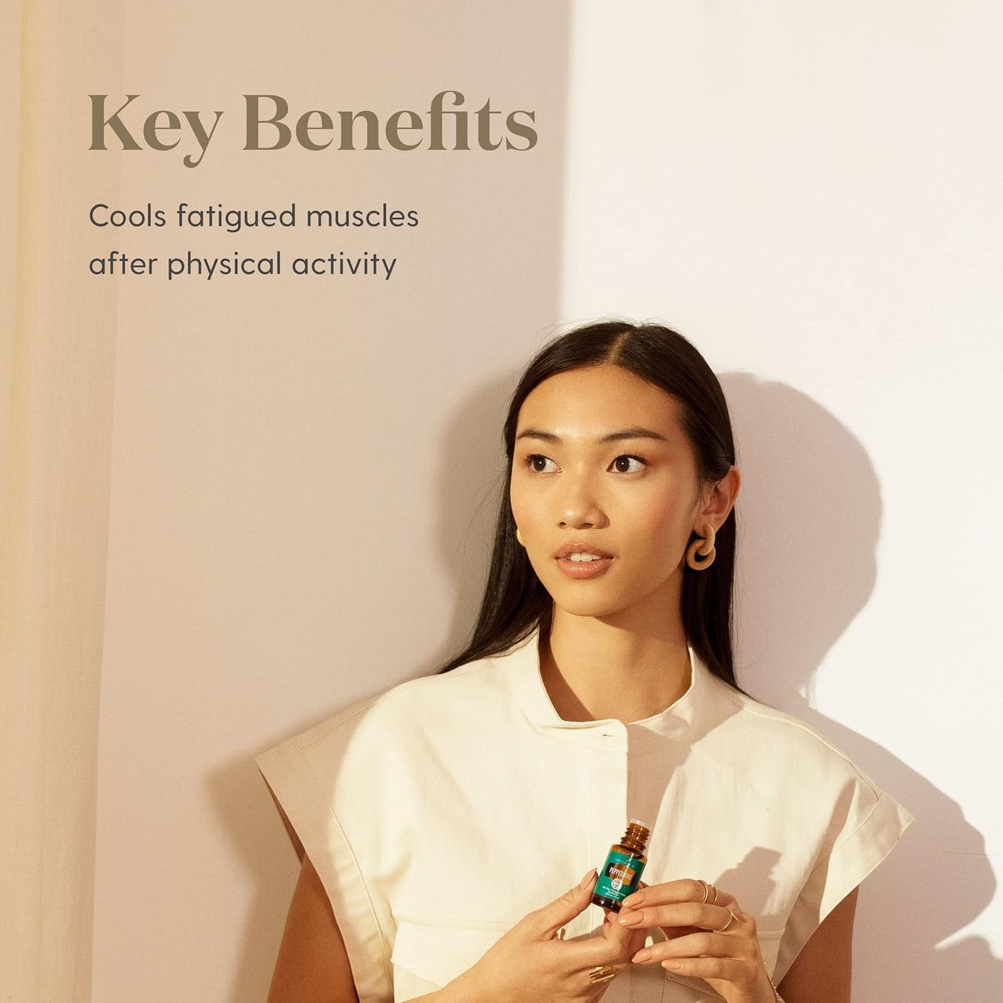 Woman holding a bottle of Young Living Peppermint essential oil highlighting key benefits.