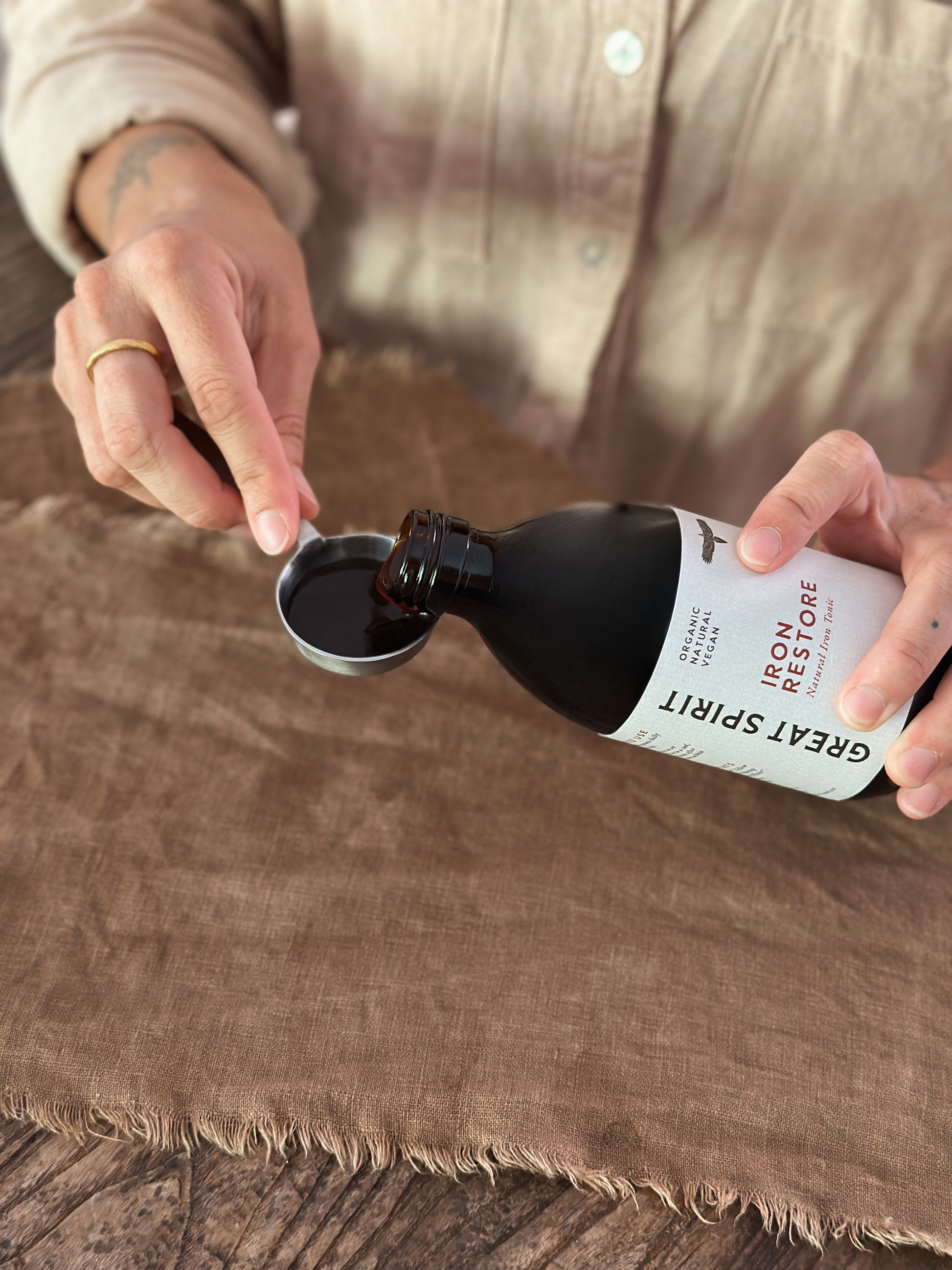 Person pouring liquid from a bottle of Great Spirit Iron Restore into a spoon.