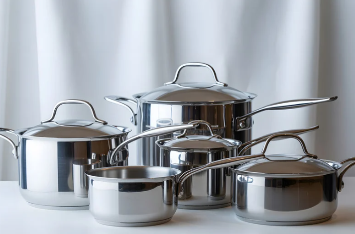 Set of stainless steel cookware with lids on a light background