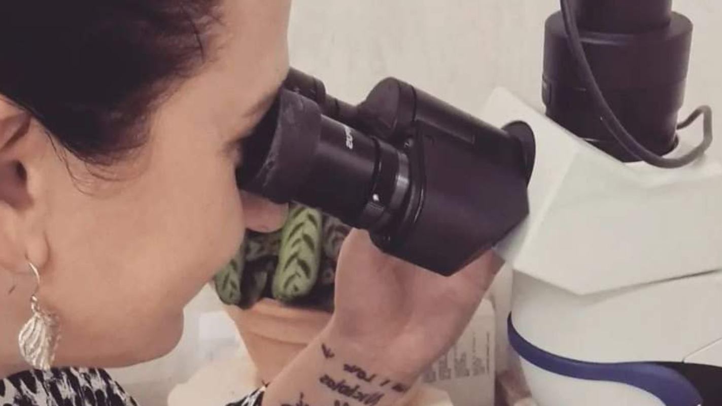 Person using a microscope with a neutral background