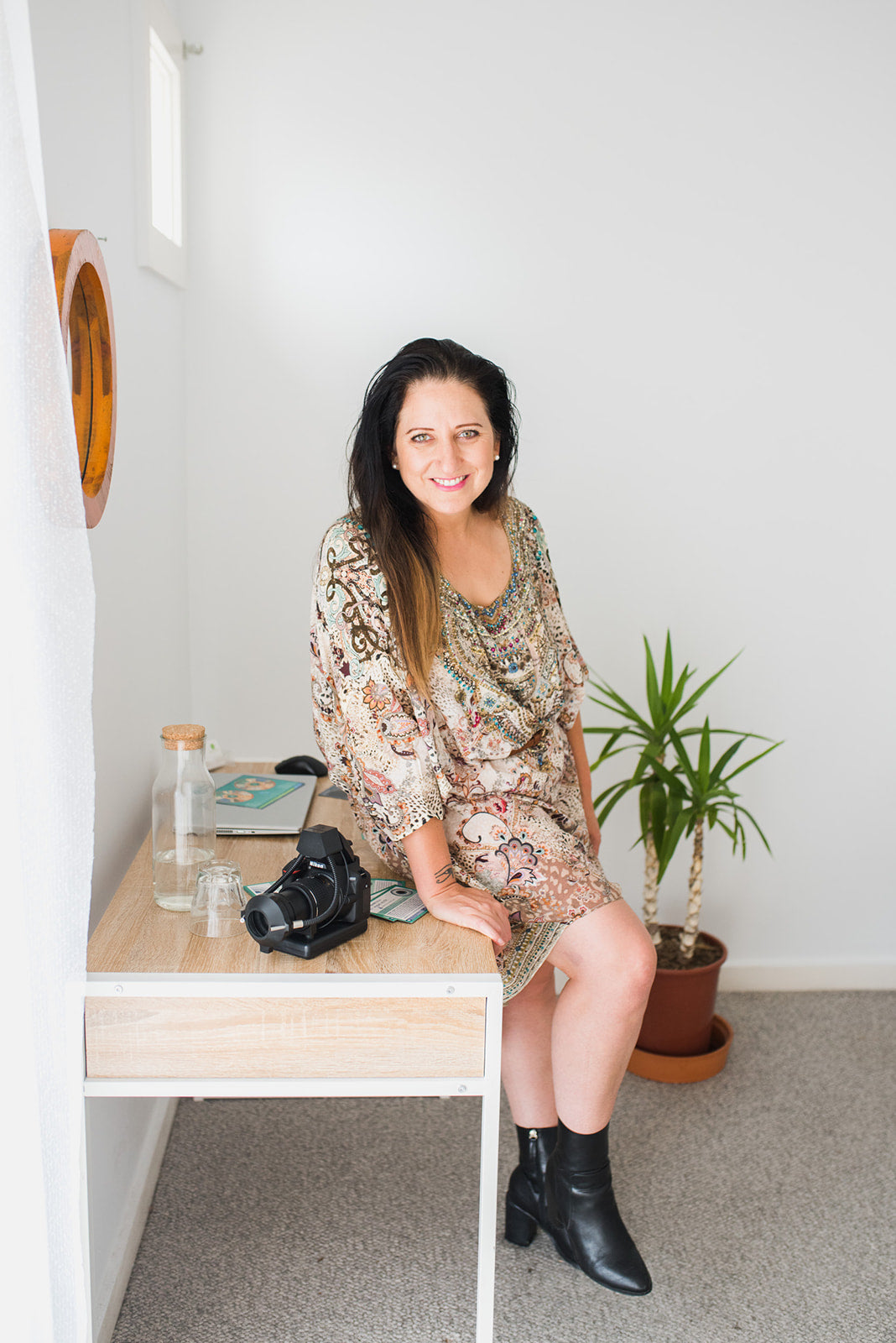 Diane Hackner sitting at a desk with a camera, plant, and iridology charts in our Preston clinic. 